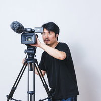 ビデオカメラのモニターを見ながら正面上を撮影する男性の写真