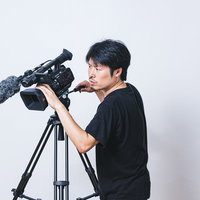 真剣な眼差しでビデオカメラを操作して撮影するカメラマンの写真