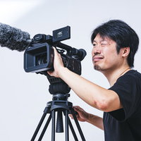 片目を閉じながらビデオカメラでムービー撮影する男性の写真