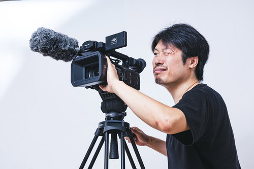 片目を閉じながらビデオカメラでムービー撮影する男性