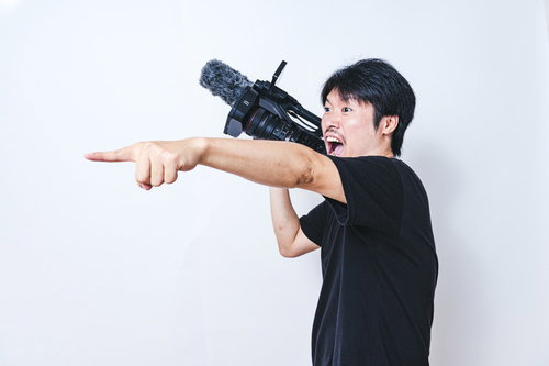 怒号が飛び交う撮影現場でビデオカメラを構えるカメラマン