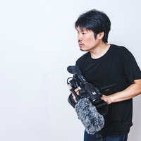 ビデオカメラを持ってスタンバる男性カメラマンの写真