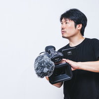 ムービー撮影に情熱を注ぐハンディカメラの男性カメラマンの写真