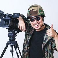 険しい撮影収録を終えたカメラマンが親指を立てるポーズの写真