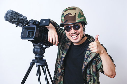 険しい撮影収録を終えたカメラマンが親指を立てるポーズ