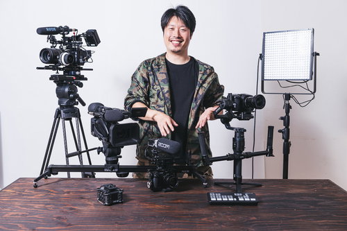 動画機材に囲まれてポーズをとる男性カメラマン