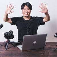 視聴者に手を振るムービー撮影中の男性配信者の写真