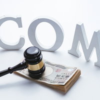 中古ドメインオークション、木製ガベルと札束、COM文字の写真