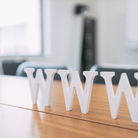 木製テーブルに置かれたWWWの白いアルファベットオブジェの写真