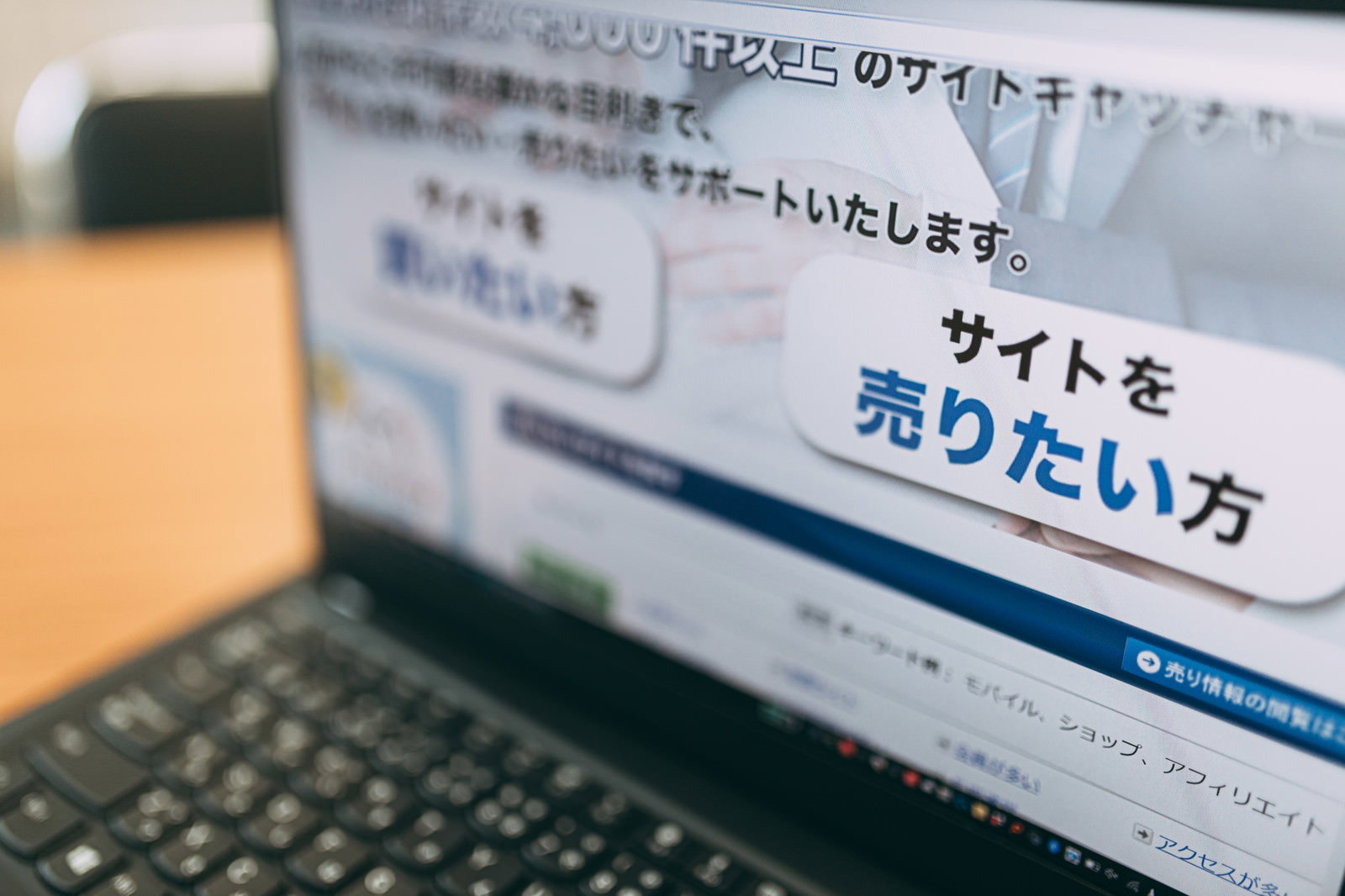 デスクに置かれたノートパソコンでサイト売買の画面を表示