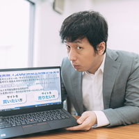 ノートパソコンで営業するグレースーツの男性の写真