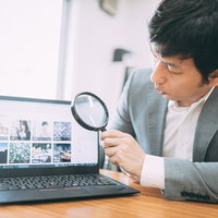 虫眼鏡でWebサイトの価格を詳しく鑑定する営業マンの写真