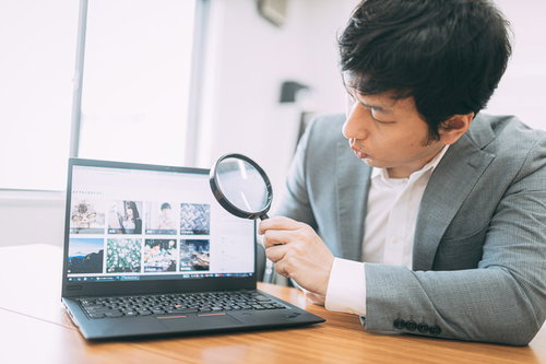 虫眼鏡でWebサイトの価格を詳しく鑑定する営業マン