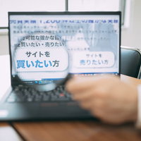 優良なサイトを買いたい方へ、ノートパソコンで情報確認する男性の写真