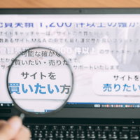 ウェブサイトを虫眼鏡で詳細に鑑定する男性営業マンの写真
