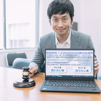 サイト売買成立時のオフィスでノートパソコンを見せるスーツ姿の男性の写真