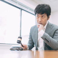 入札価格を下げるか悩むオークションのベテラン男性の写真