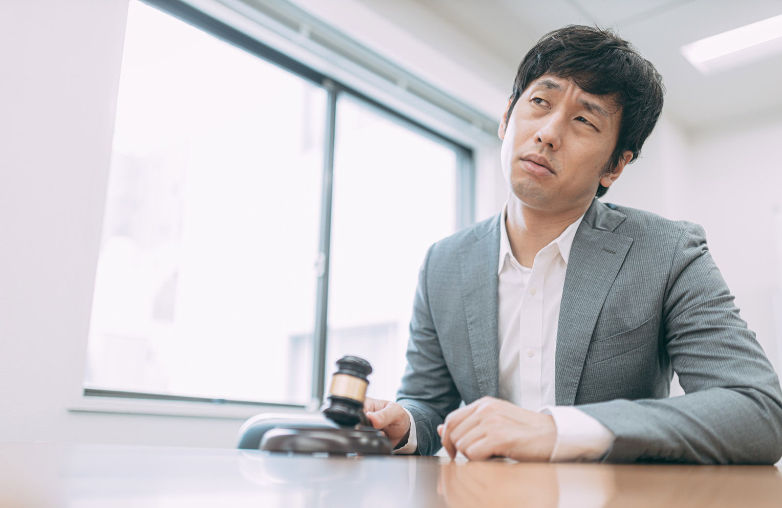 落札結果に不満を抱きうなだれるグレーのスーツを着た会社員男性［モデル：大川竜弥］