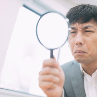 虫眼鏡を持ってサイト鑑定中の男性エージェントの写真