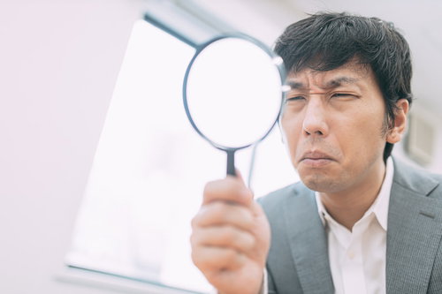 虫眼鏡を持ってサイト鑑定中の男性エージェント