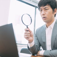 成果が見込めないサイトを虫眼鏡で鑑定する男性の写真