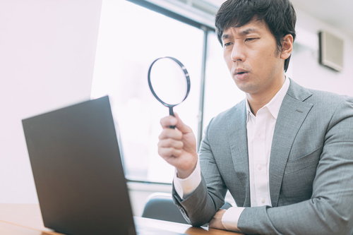 成果が見込めないサイトを虫眼鏡で鑑定する男性