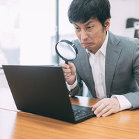 鬼の形相でバグチェックをする虫眼鏡片手の主任の写真