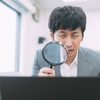 虫眼鏡でノートパソコンの画面を鑑定するサイト売買エージェントの写真