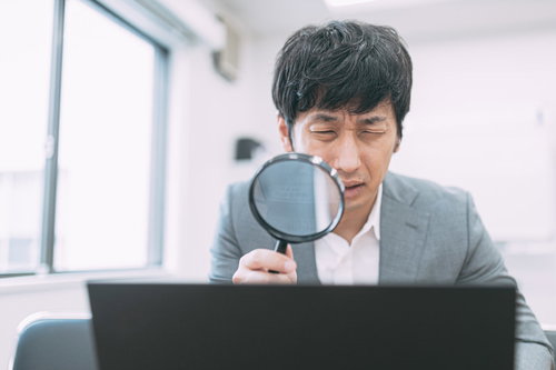 虫眼鏡でノートパソコンの画面を鑑定するサイト売買エージェント