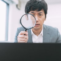 サイト売買の価値を虫眼鏡で鑑定する男性エージェントの写真