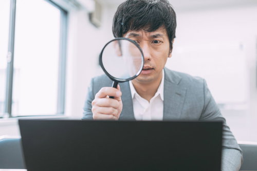 サイト売買の価値を虫眼鏡で鑑定する男性エージェント