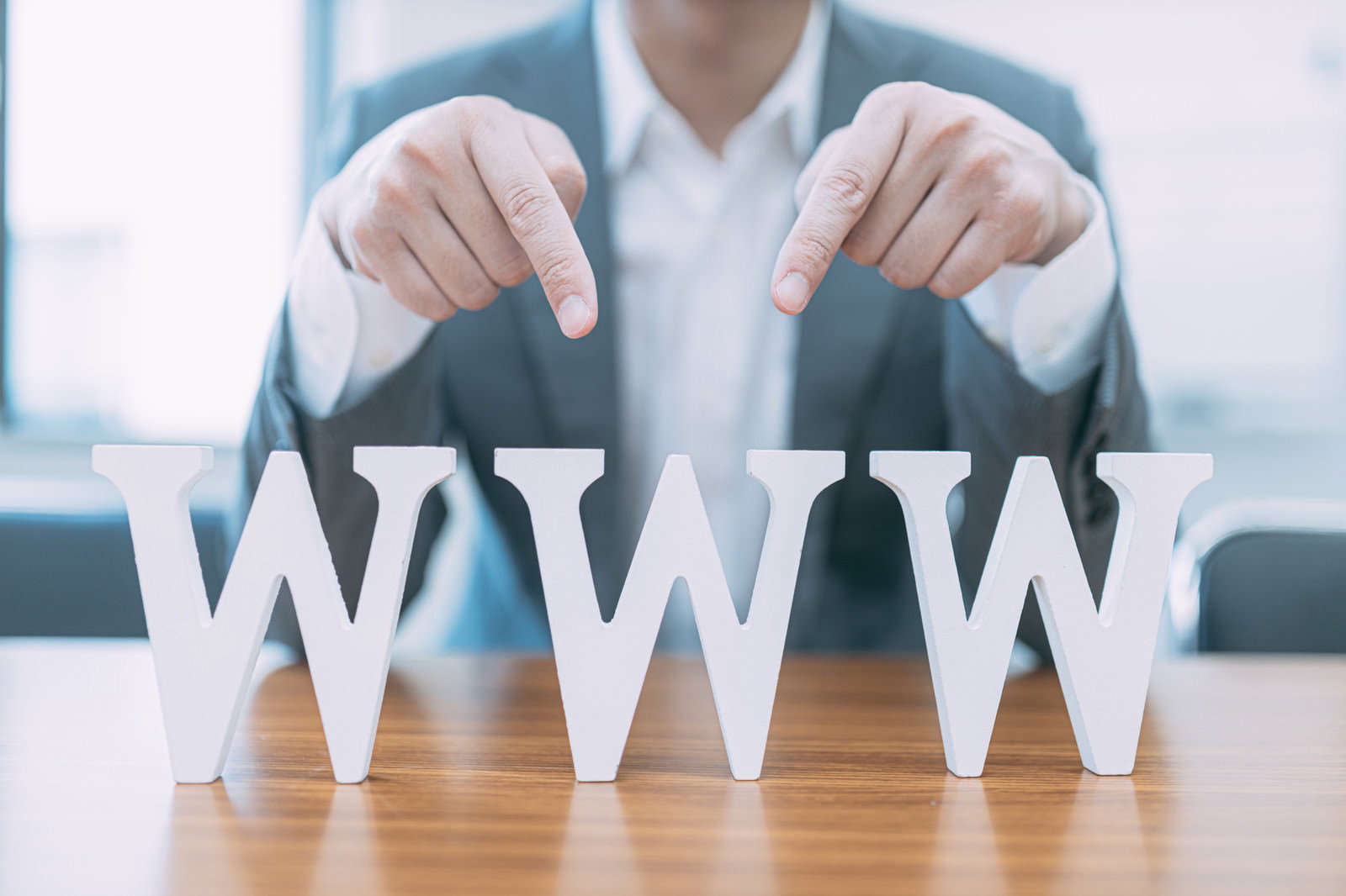 WWWの立体文字を指さすスーツの男性［モデル：大川竜弥］