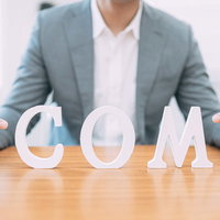 ドメインは .com（ドット混む）でキマリ、親指を立てるビジネスマンの写真