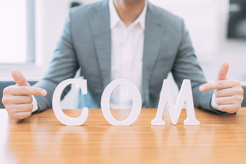ドメインは .com（ドット混む）でキマリ、親指を立てるビジネスマン