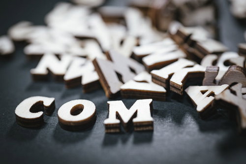 散らばったアルファベットと.comドメイン
