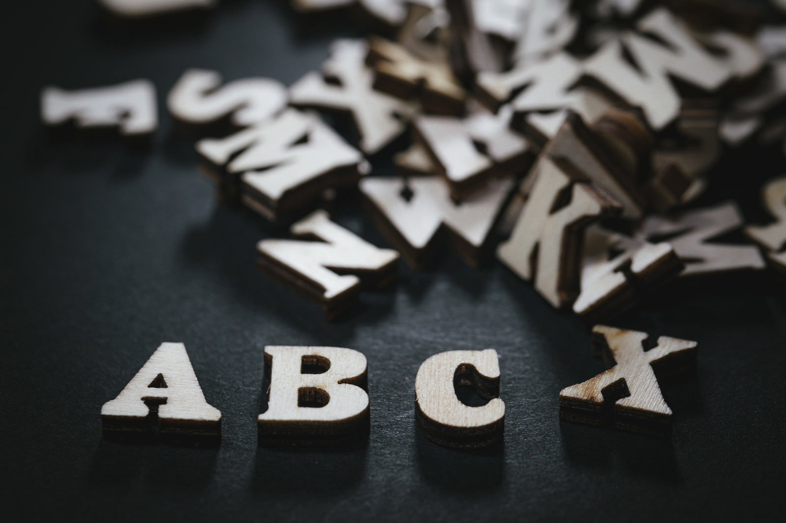 暗い背景に散らばる木製の英文字とABCの文字