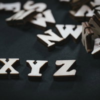 黒い背景に散らばる木製の英文字ブロックとXYZの写真
