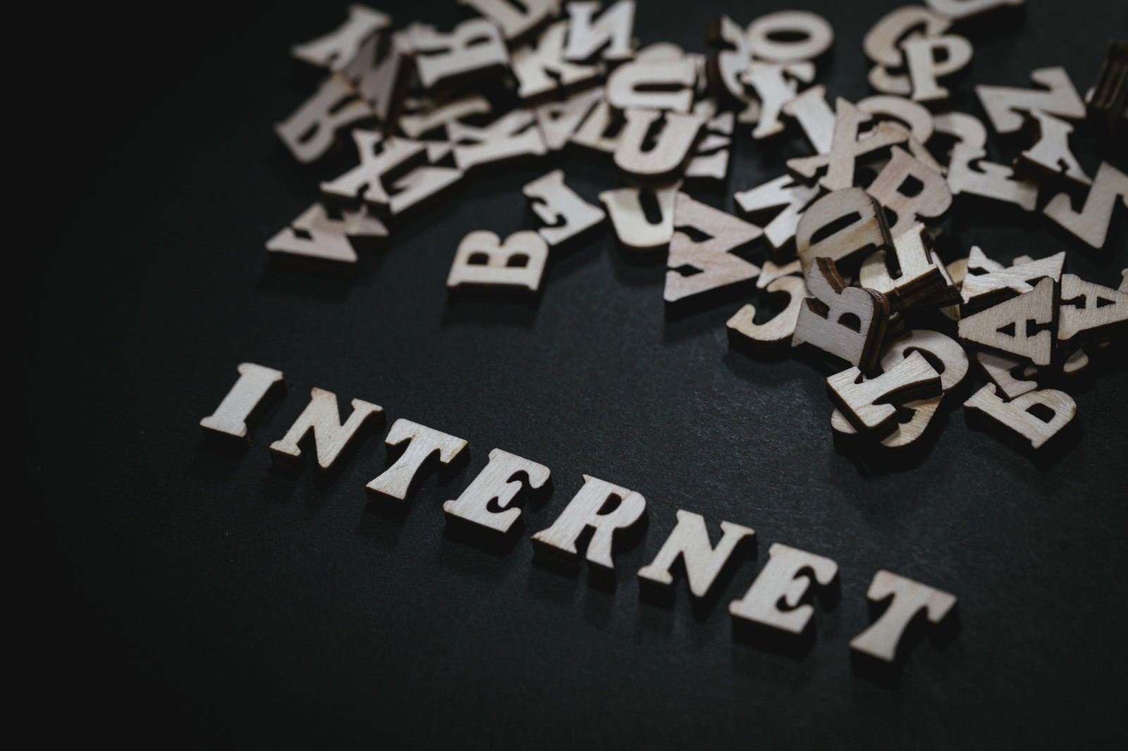 黒い背景に白い「INTERNET」の文字とアルファベットが散らばっている