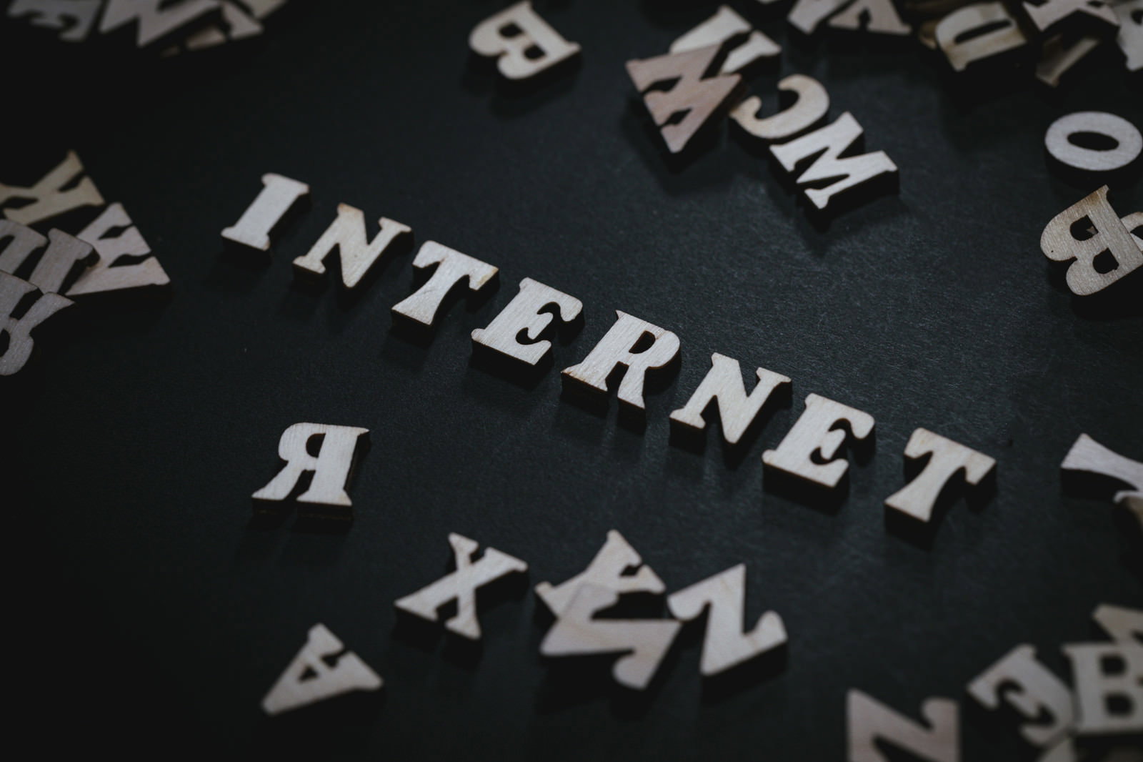 黒い背景にINTERNETの白文字とアルファベットが散らばる写真