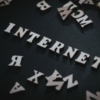 黒背景に白く映るINTERNETの文字と英文字が散らばるデザインの写真