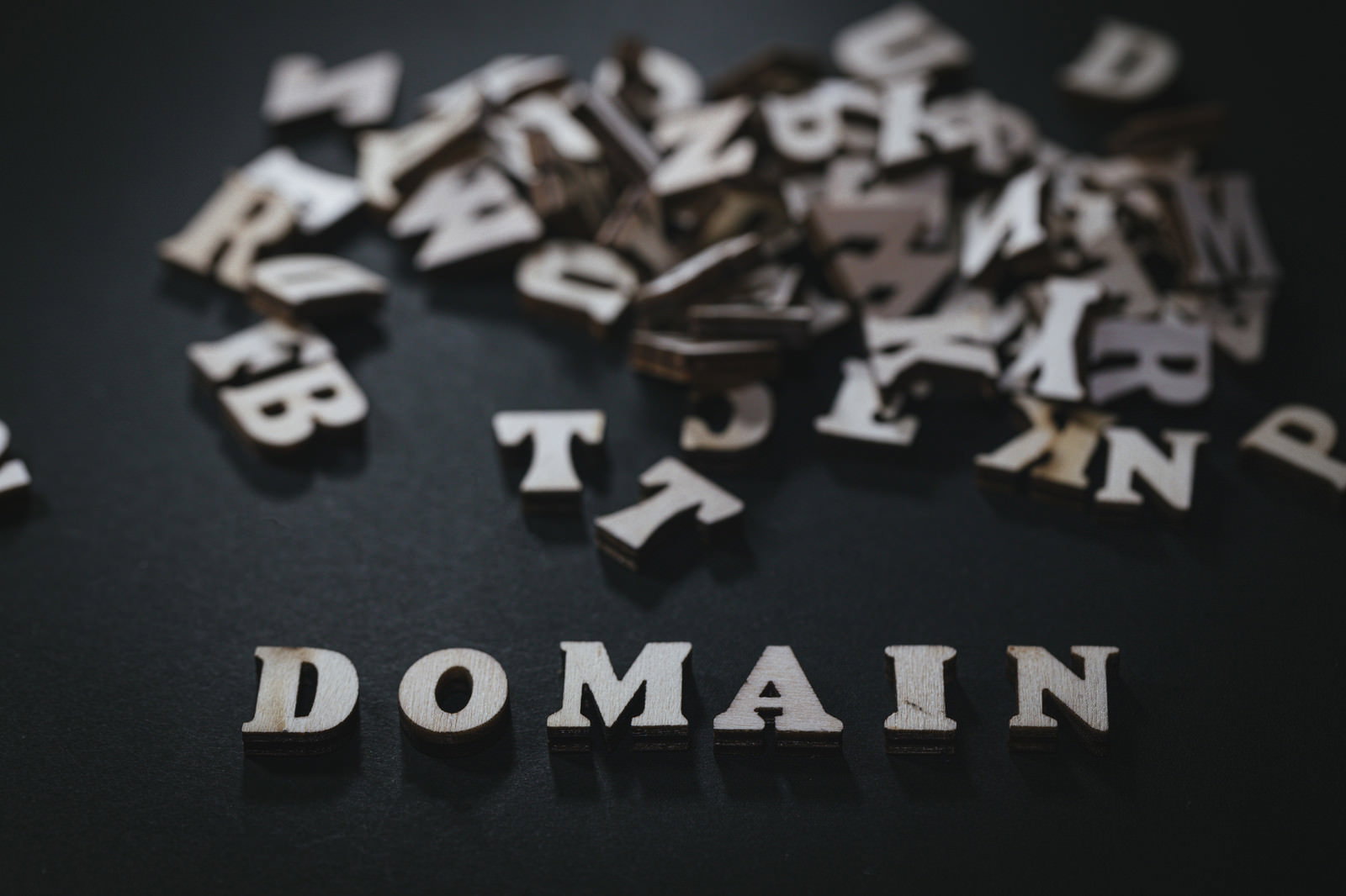 黒い背景に散らばったアルファベットとDOMAINの文字