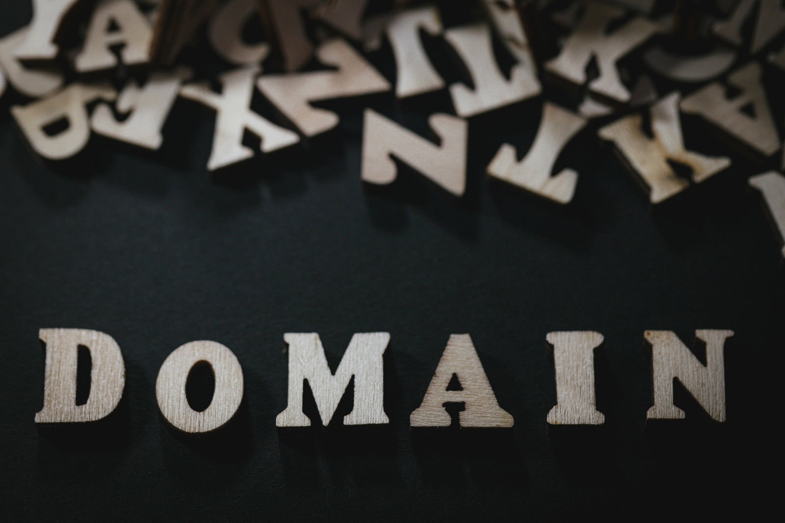 黒背景にDOMAINの白い立体文字と散らばったアルファベット