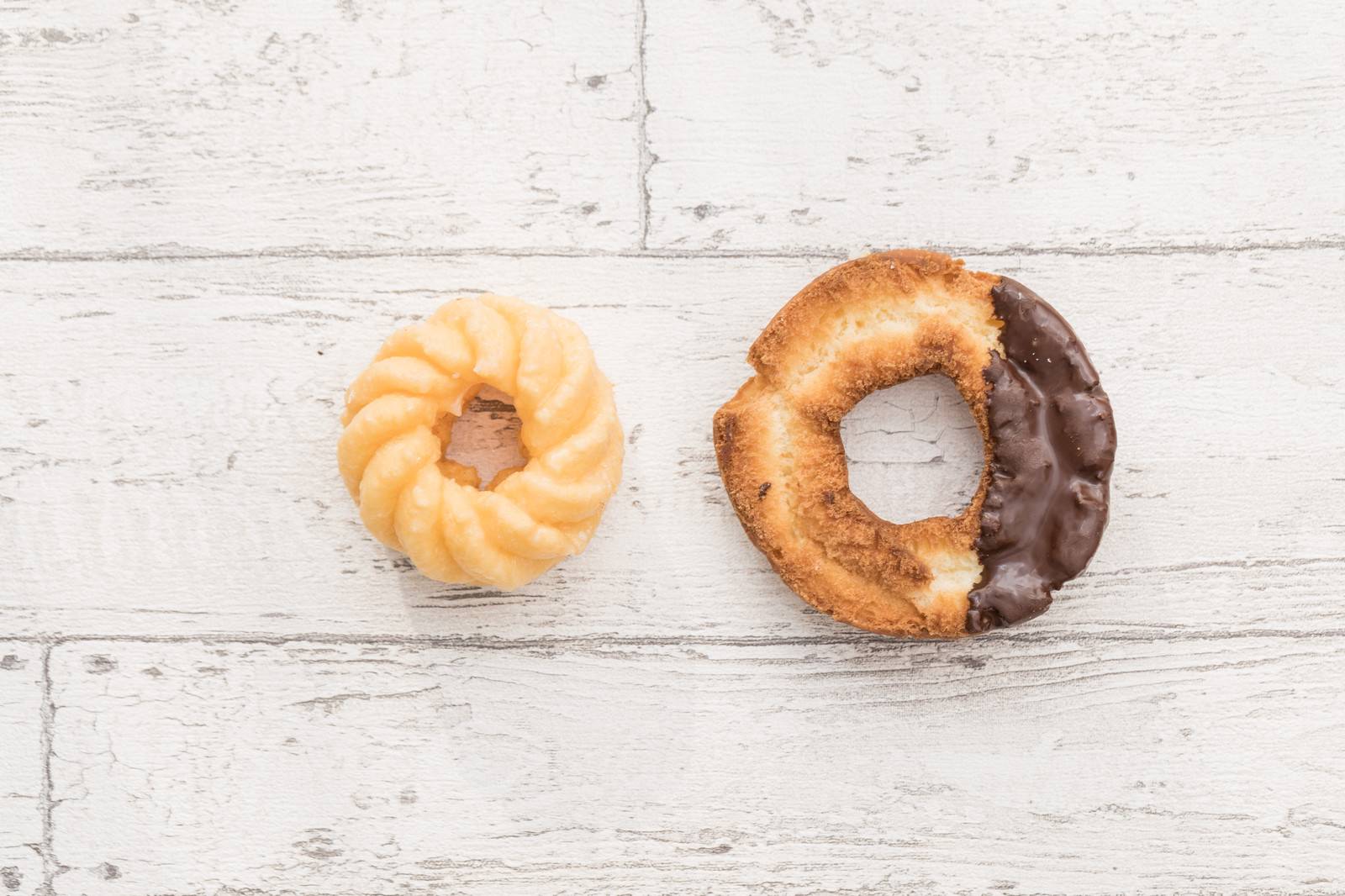 白い木目の背景に置かれたフレンチクルーラーとチョコレートのオールドファッション