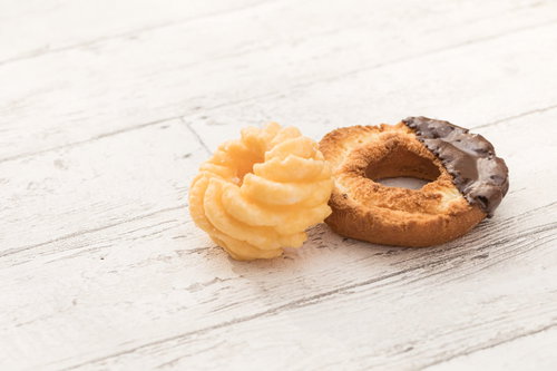 白い木目背景に並ぶフレンチドーナツとオールドファッション