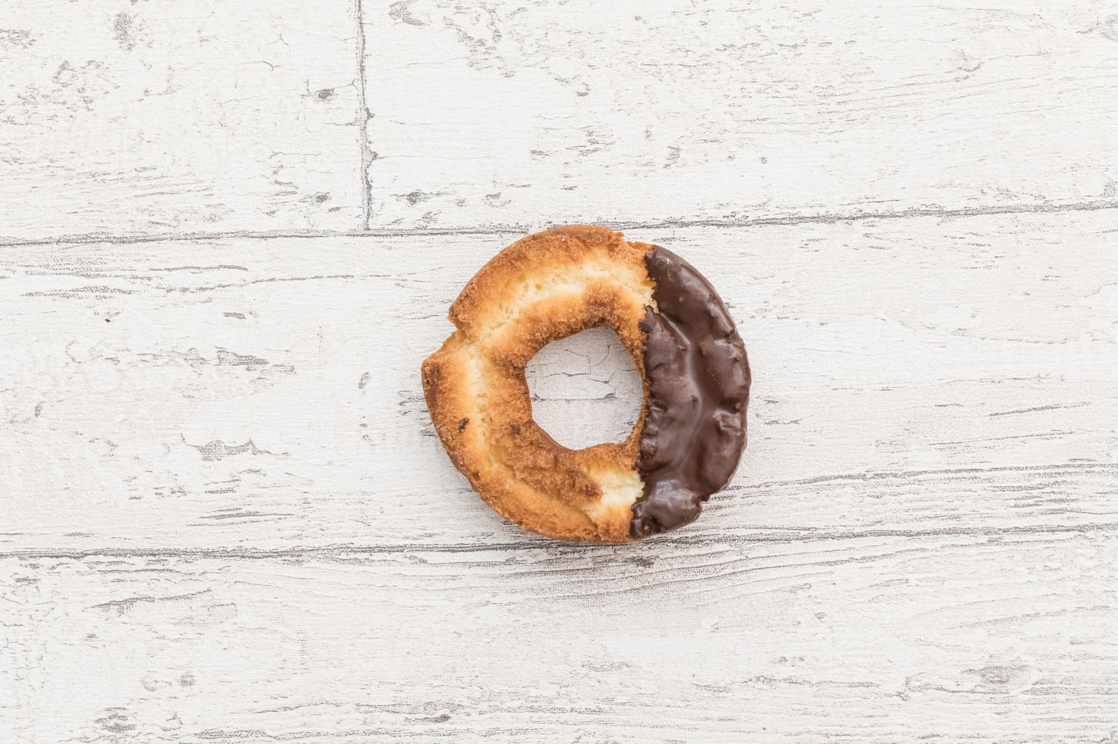 白い木目調の背景に置かれたオールドファッションドーナツ