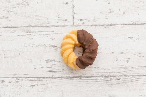 甘いチョコレートのフレンチクルーラー、白い木目背景に置かれた2色のドーナツ