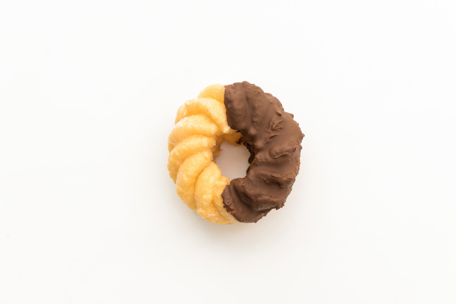 白い背景に置かれたチョコが半分ついたドーナツ