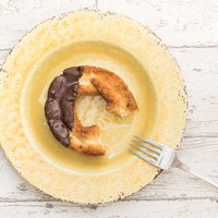 黄色いお皿に置かれた食べかけのオールドファッションドーナツの写真