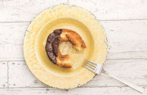 黄色いお皿に置かれた食べかけのオールドファッションドーナツ