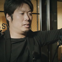 ビデオカメラを背負ってダメ出しする男性監督の写真